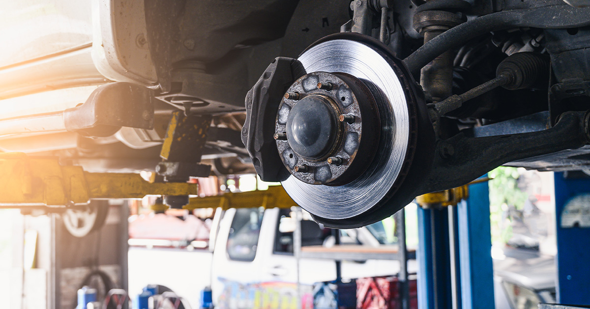 A close-up of a brake and rotor of a vehicle on a lift in the service center.