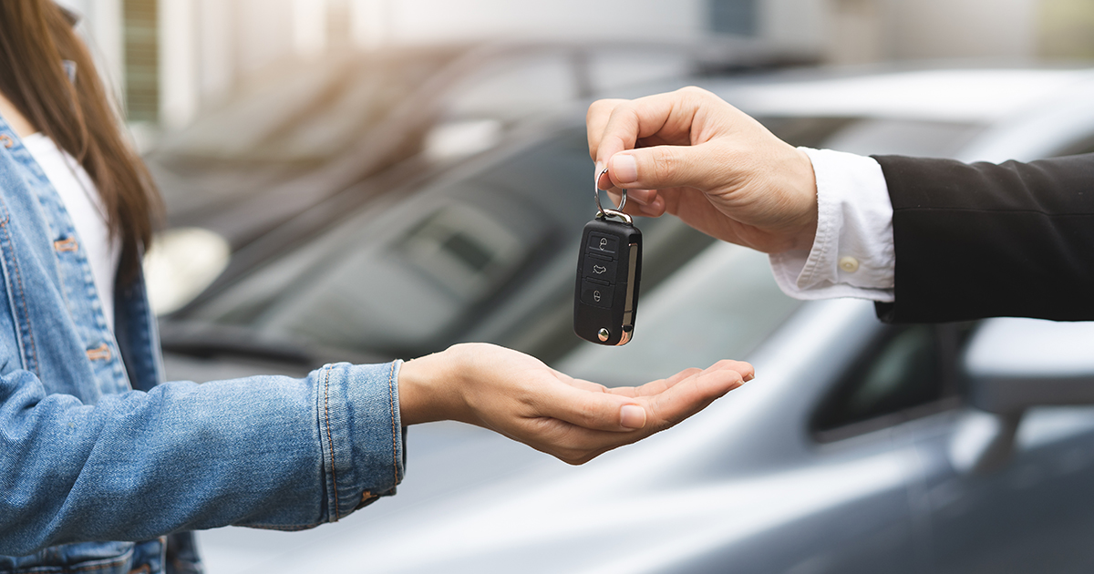 Close-up of a sales person's hand handing over car keys.